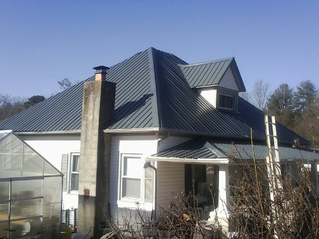 Dark blue standing seam metal roof on a white farmhouse with dormer — Slate & Tile Roof Repair by Roofing Brothers in Athelstane