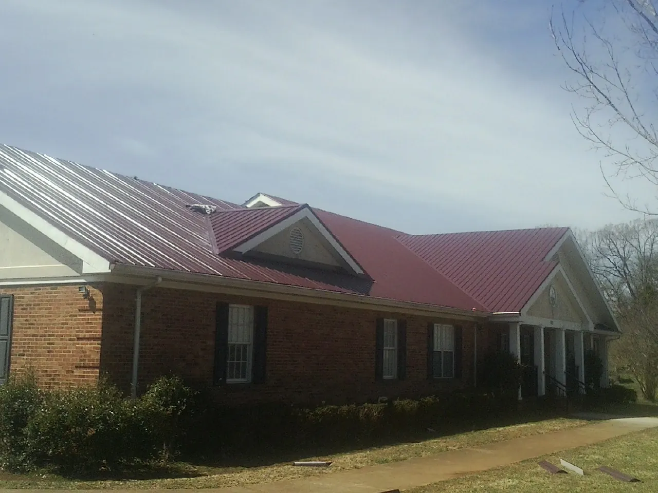 Red metal roof with gabled entries on a long brick building in Athelstane