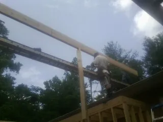Carpenter setting a ridge beam over a new addition frame — Ice Dam Removal by Roofing Brothers in Athelstane