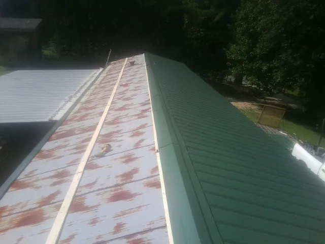 Old rusted panels beside newly installed green metal roofing — Wind Damage Roof Repair by Roofing Brothers in Athelstane