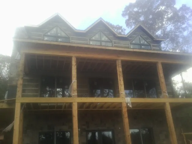 Dormers and porch framing on a large log home under construction — Roof Coating work by our crew in Athelstane