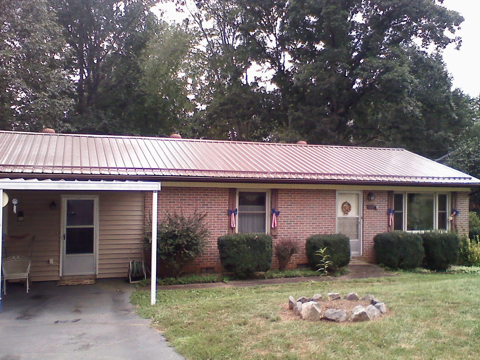 Bronze metal roof and carport on a brick ranch home — Roof Repair work by our crew in Athelstane